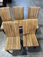 Top angled view of five wicker chairs arranged in a circular layout, showing woven seat and back detail and dark wooden legs.