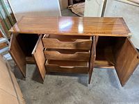 Front view with doors open showing three center drawers and side storage compartments