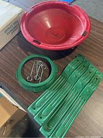 Red metal basin, green metal legs, and screws shown with original box partially visible