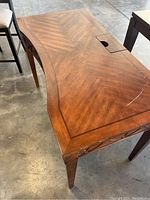 Top view of wooden desk showing patterned wood grain surface with a visible scratch and slot for cable management