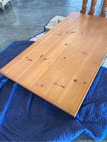 Close-up of rectangular wood dining table top showing natural knots and scratches.