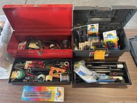 Shows open red and black toolboxes filled with various soldering and electrical tools, connectors, wires and flux