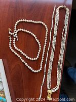 Photo showing three single-strand pearl necklaces and one multi-strand pearl necklace.