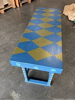 Top view of rectangular wooden side table showing hand painted blue with olive green diamond pattern.