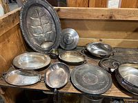 Wide view of all silver servingware items displayed on wooden surface