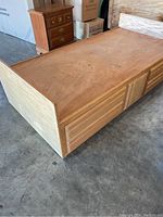 Single wooden bed frame with underbed storage drawers, showing scratches and wear on surface.