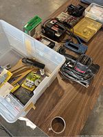 Craftsman finishing sander, Skil jigsaw, stapler, multimeter, clamps, socket set and various tools on wooden table plus plastic bin with hand tools