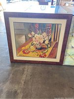 Framed floral artwork showing vase of flowers on patterned table