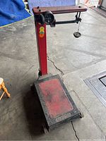 Full view of the red Fairbanks warehouse hand scale with base platform, vertical pillar, horizontal arm, and hanging weight