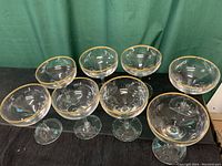 Front view of all eight crystal wine/champagne glasses arranged closely, showing shape, design, and gold rim.