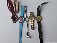 Full view of the five women's wristwatches laid flat, showing different sizes, colors and bands.