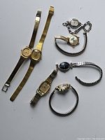 Seven vintage women's wristwatches arranged on white surface showing different styles and metal tones.
