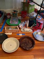 Image showing the array of baking items including trays, cake pan, pie plates, wooden box of cookie cutters, rolling pins, aprons, and decorative butter dish.