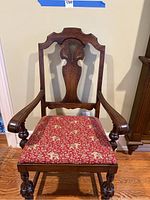 Full front view of dark wood carved armchair with upholstered red fabric seat featuring elephant motifs.