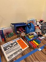 Photo showing boxed Creative Playthings aluminum xylophone, colorful wooden xylophone, woven basket with tambourine, assorted books, and assortment of toys and stuffed animals