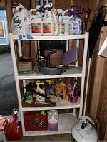 Shelves filled with various gardening pesticides, lawn care products in spray bottles, garden pots, hand tools, brushes, and potting soil bags.