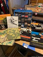 Overview of 4 G.I. Joe squad leader themed board games displayed on a table with maps, instruction booklets, and blue plastic box containing game pieces.