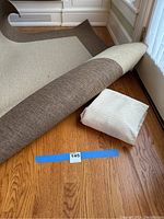 Indoor/outdoor area rug partially rolled showing front pattern and backing, with the folded backing material next to it on hardwood floor.