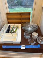Photo showing expandable white plastic utensil organizer with assorted utensils, two-tier bamboo utensil organizer, nested glass mixing bowls set, and small prep bowls.