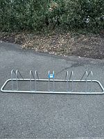 Full view of the entire metal bicycle rack showing the rectangular base frame with five wheel loops spaced evenly.