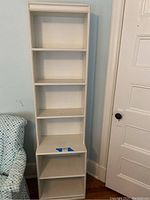 Full view of the tall, narrow white bookcase with six shelves, showing bottom two shelves are open, measures approximately 18 x 12 x 70 inches.