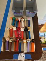 23 assorted PEZ candy dispensers featuring various characters laid out on a table from an overhead view, including a mix of cartoon, comic book, and holiday characters.
