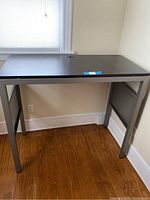Front and side view of the standing desk showing the metal legs, vented metal support panel, and wood top.