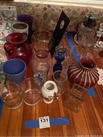 Lot of 19 vases of various sizes and colors arranged closely together on a wooden surface.