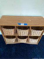 Front view of the wooden storage shelf with all 6 wicker baskets inside the cubbies.