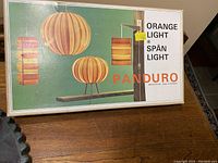 Box top showing vintage Danish Panduro branding and images of assembled lamps in orange and wooden finishes.