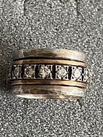 Close-up front view of Alessio sterling silver spinner ring showing hammered silver bands and row of clear round gemstones on central band.