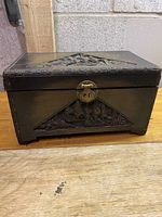 Front view of the rectangular carved wood box with metal latch, showing detailed craftsmanship and carved design panels.