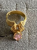 Front view of the gold coloured ring showing the band details and pink stone in prong setting.