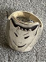 Close-up photo of sterling silver face ring showing carved facial features and patina.