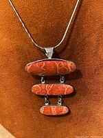 Front view of the necklace showing the coral pendant with three connected oval-shaped stones and the upper silver chain.
