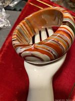 Close-up side view showing the glossy resin finish and multi-color stripe pattern of the bangle.