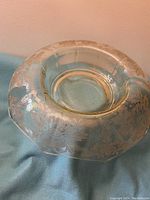 Side view of the round rolled edge depression glass bowl showing floral etched details and rounded form
