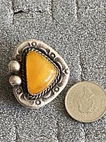 Front view of the vintage sterling silver ring with triangular butterscotch stone and silver detailing next to a Canadian quarter for size reference