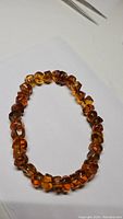 Photo showing chunky rondel cut baltic amber beads in bracelet form on white background, displaying a warm golden maple amber color.