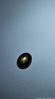Close-up image of 2.23ct oval cabochon black star sapphire showing the 6-ray star effect on a light background.