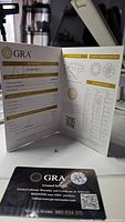 Open GRA certificate showing grading report details for round Moissanite, including measurements, clarity, and color grading.
