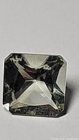 Close-up photo of the square cut natural green amethyst gemstone showing faceting and clarity from one angle.