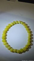 Front view of the lemon jade bead bracelet with smooth, round beads visible.