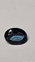 Close-up image of a single oval London Blue Topaz gemstone showing its deep blue color and faceted cut.