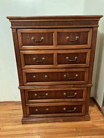 Full front view of wooden chest showing all drawers and handles, surface with visible wear marks