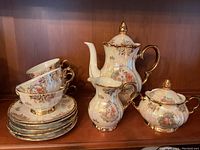 Full set including teapot, creamer, sugar bowl, 3 cups, and 5 saucers arranged on shelf