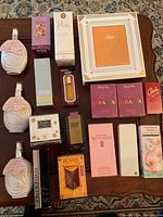 Overview of perfume and fragrance bottles and boxed sets laid out on a brown surface, showing all items from the lot.