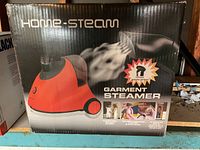 Front of the original box showing Home-Steam brand garment steamer emitting steam, with usage images and branding.