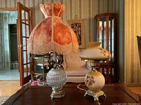 Photo showing both vintage table lamps on a wooden surface in a room with antique-style decor.