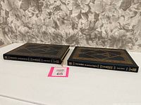 Two blue leather-bound collectible Easton Press books, spine view showing titles and gilt baseball bat decoration.